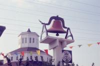 red starting bell at Red Mile Racetrack in center of photograph with white roundbarn in the background.