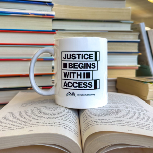 Mug with "Justice begins with access" graphic on a stack of books
