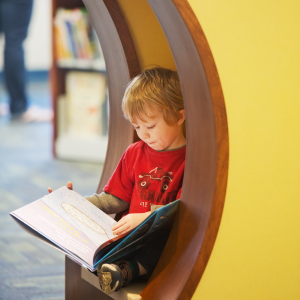 A young child reads book at the library