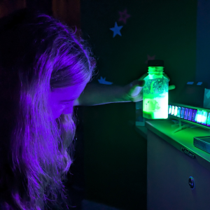 School-aged child holds a green glowing bottle in their hand