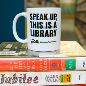 "Speak up, this is a library" mug sits on a stack of library books