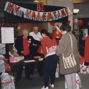 Patrons stand in line at Central Library under a "Be My Valentine" banner. Scanned film image from 1996. 