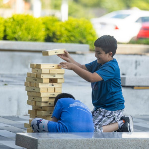 Two children patrons play a giant jenga game outside of Marksbury Family Branch