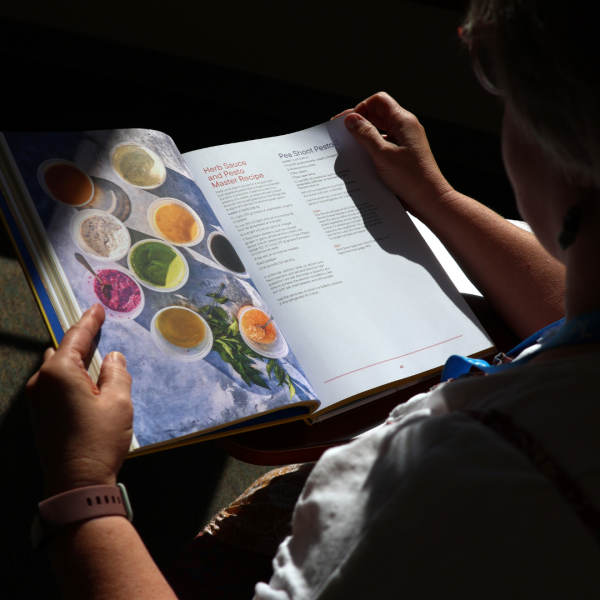 Librarian reads cookbook, available at all locations, in a sunny spot of Tates Creek Branch. Browse the catalog now to find your next recipe.