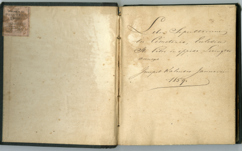 Two page book spread with a stamp on the left hand side and Latin text on the right hand side that means "Book of those buried in the St. Peter church cemetery in the City of Lexington. Written the first of January 1859."