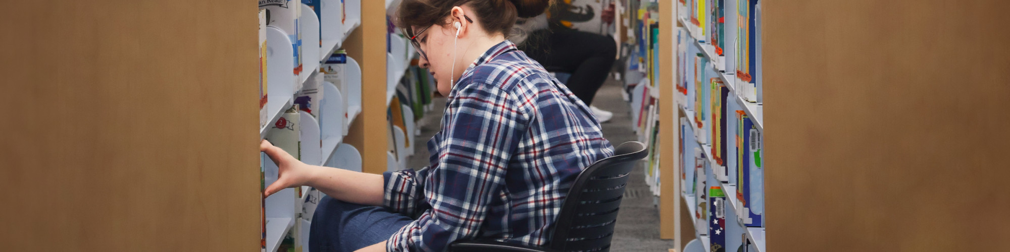 Library staff member sorting items in the book stacks