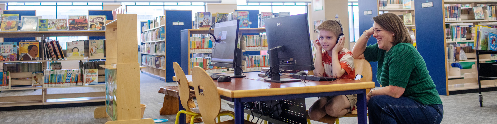 A woman helps a child use the computer
