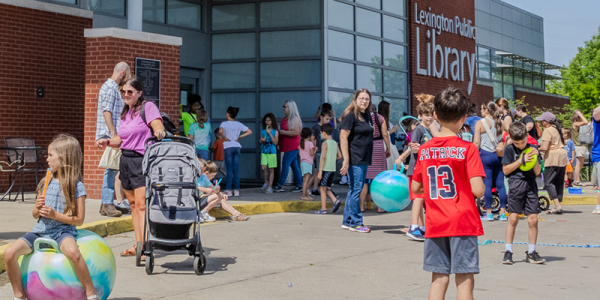 Families play outside Northside Branch at the Summer at the Library kickoff party