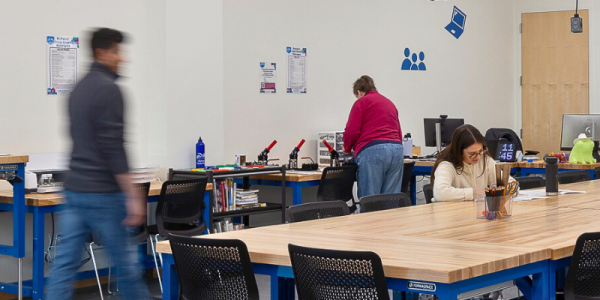 Library patrons work on craft projects at a community table in the Makerspace