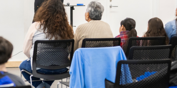 All-ages of patrons sit facing the front of the room to listen to an author talk