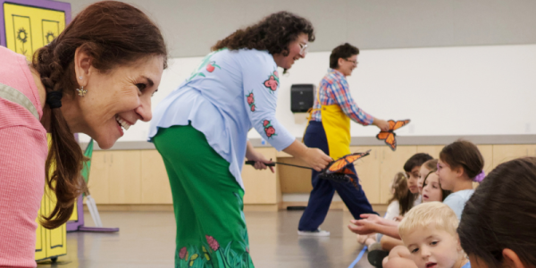 Three actors from the Lexington Children's Theatre present Mariposa/Butterfly and interact with children in the front row using puppet butterflies.