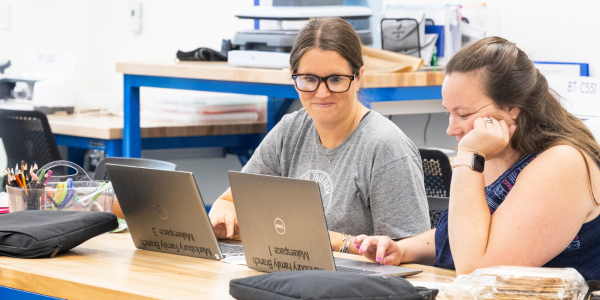 Two teachers look at laptops during Teacher Time at the Makerspaces