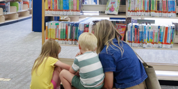 Children and caregiver look for books.